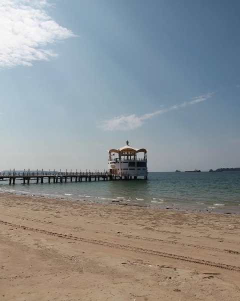 A long wooden pier extends into the ocean in Labuan.