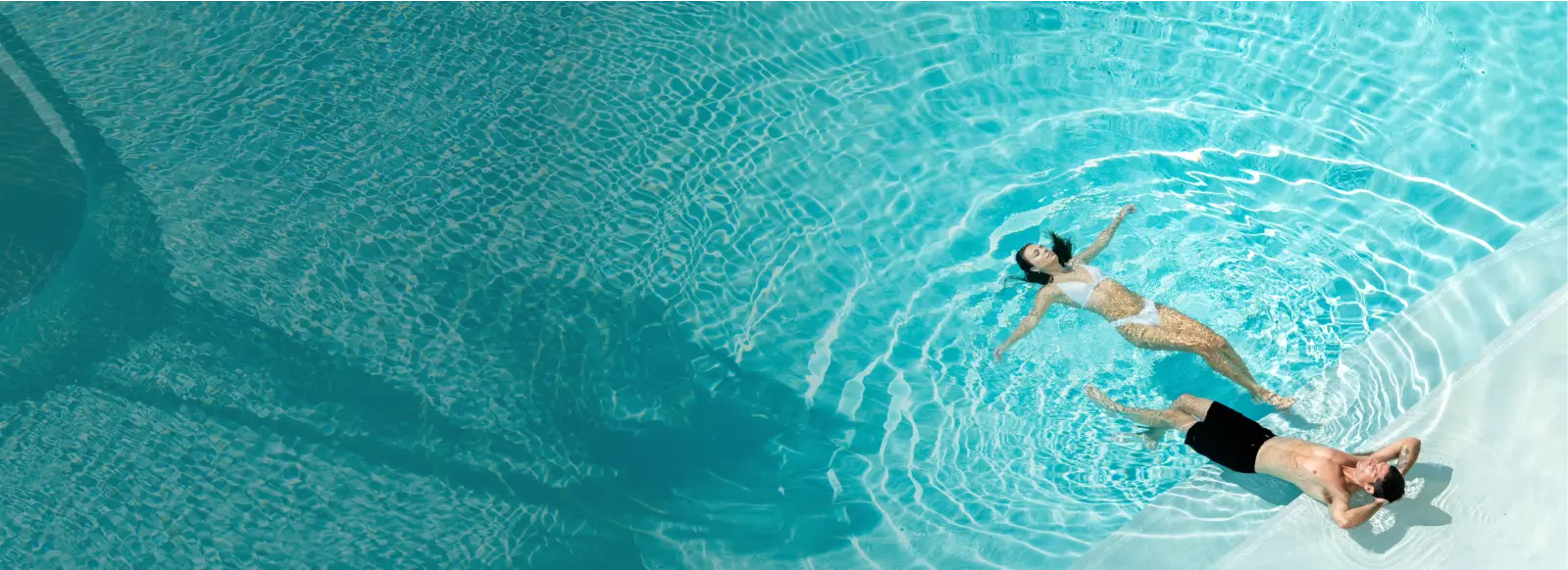 A couple enjoying a peaceful moment in a stunning turquoise pool.