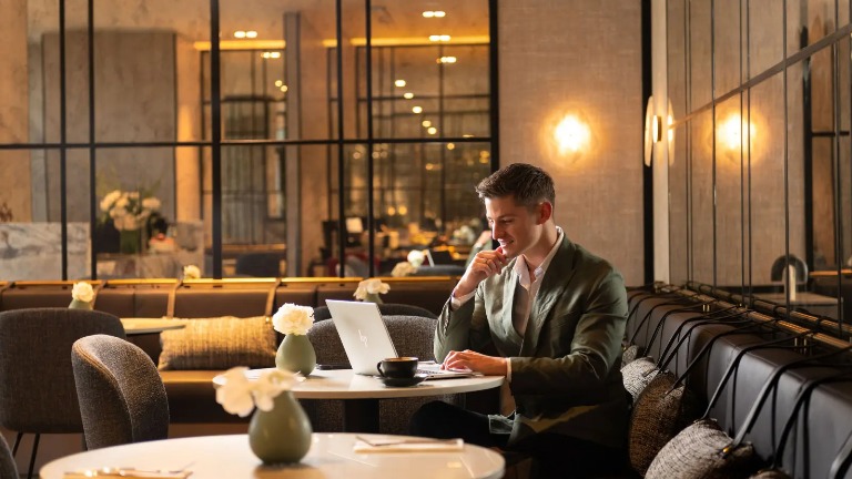 Man in a suite using his laptop and having a coffee.